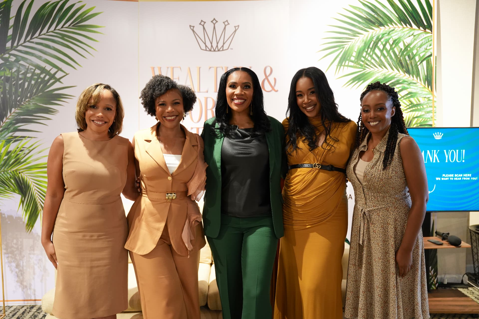 Five attendees posing before the Wealthy & Worthy event backdrop